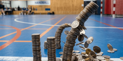 Several stacks of coins on a blue indoor court, with one stack toppling and coins falling.