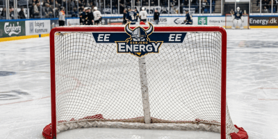 Hockey goal bearing the Esbjerg Energy logo before a crowded arena